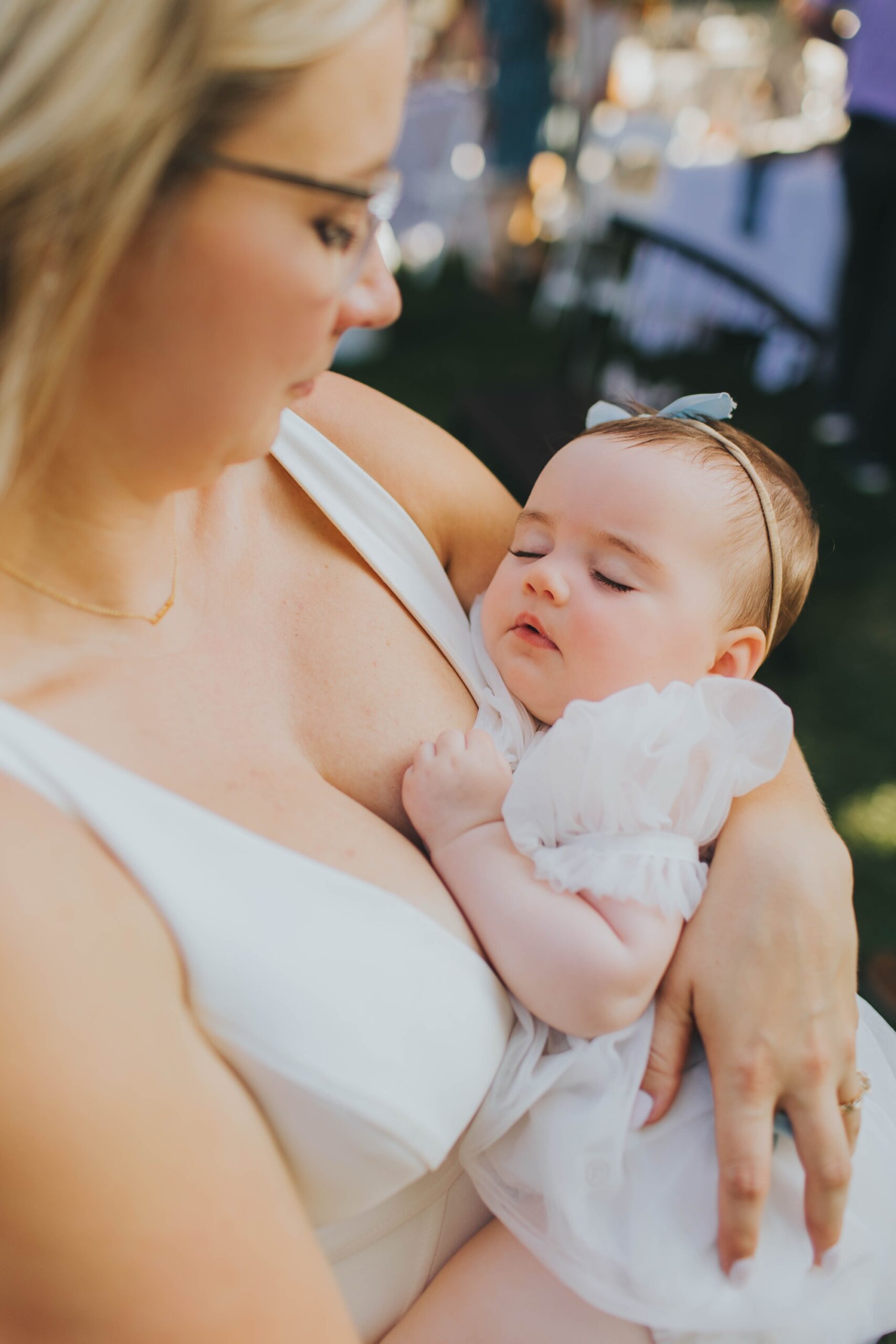 Baby girl in white dress with blue bow at Oak Forest wedding